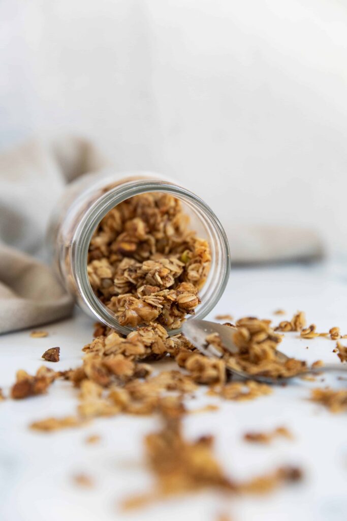 spilled jar of easy and healthy vegan and gluten-free granola with spoon next to it with granola on spoon