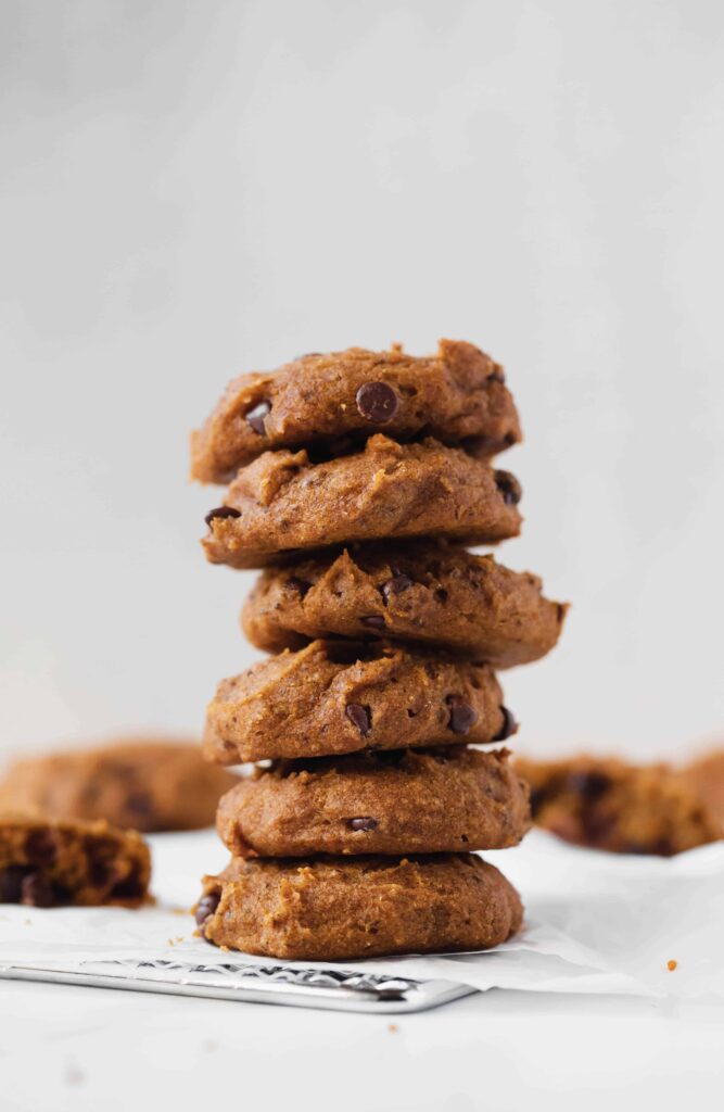 stack of the best soft pumpkin chocolate chip cookies with cookies scattered in background