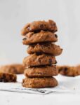 stack of homemade pumpkin chocolate chip cookies with cookies scattered in background